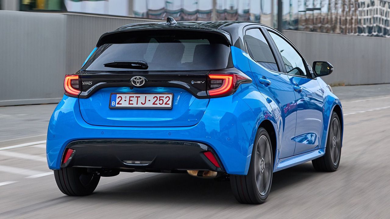 Vista posterior lateral del Toyota Yaris Hybrid circulando por carretera urbana