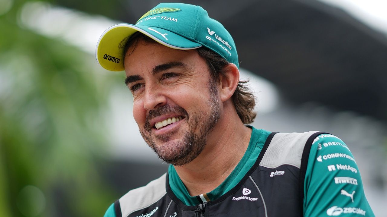 Fernando Alonso, vestido con ropa oficial de Aston Martin, sonríe en el paddock de la Fórmula 1.