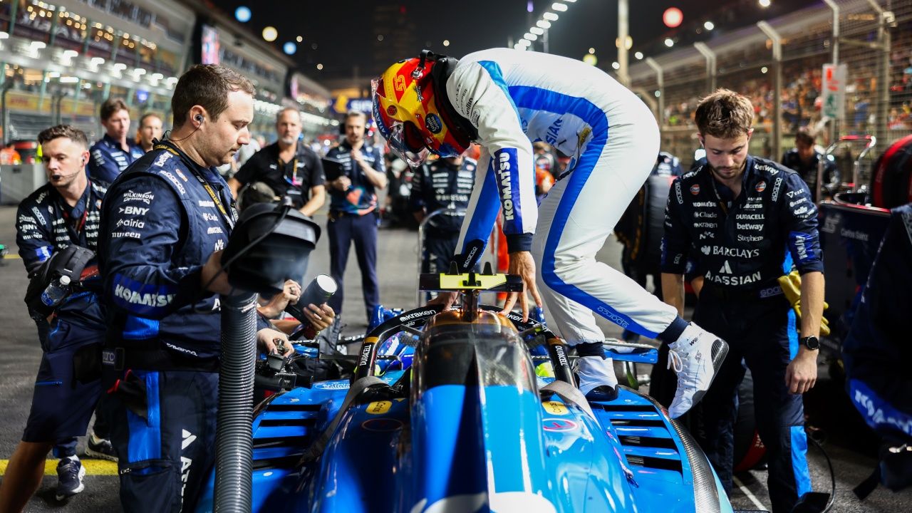 Carlos Sainz sale de su monoplaza, mientras sus mecánicos observan y preparan el coche para comenzar la carrera en Singapur.