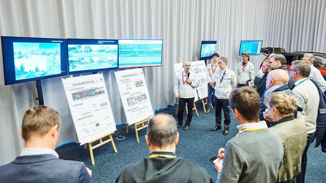Presentación de Toyota sobre conducción autónoma, con pantallas y paneles, ante un grupo de asistentes