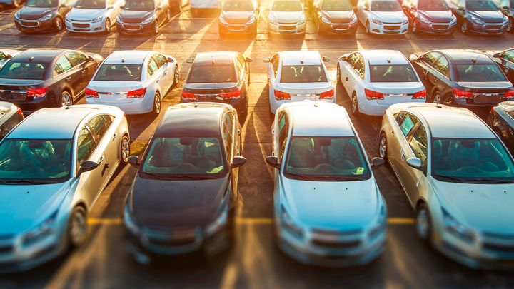 Hileras de coches nuevos aparcados en la campa de un concesionario