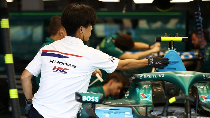 Ingeniero de Honda trabaja en un monoplaza de Aston Martin F1 en el garaje de un circuito.