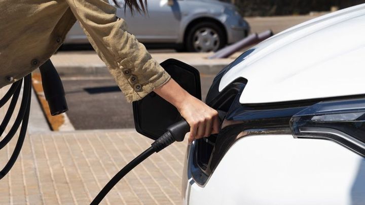Un coche eléctrico es enchufado para cargar su batería.
